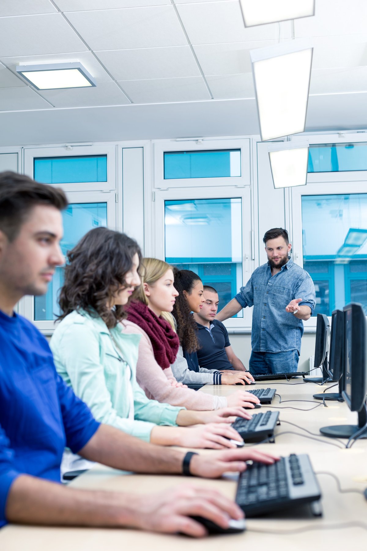 Profesor y alumnos en clase de computación con software CAD